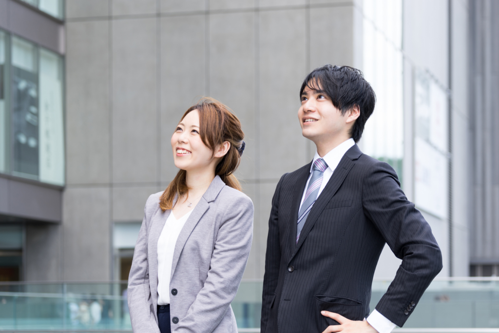 Business man and woman looking up at corporate office building